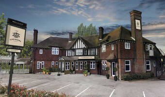 Um edifício tradicional com uma placa indicando o pub 'The Chequers', apresentando um estilo arquitetônico clássico com tijolos e estrutura de madeira branca.