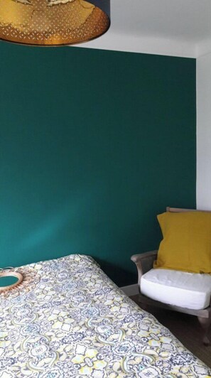 Een kamer met een bed, een stoel en een groene wand.