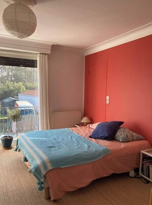 Relax in this inviting bedroom with a large bed, a red accent wall, and a window offering a view of the outside.