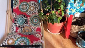 Ein Zimmer mit einem bunten, gemusterten Sessel, einer Topfpflanze und einer blauen Wand.