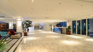 A spacious lobby with a marble floor, seating areas, a reception desk, and potted plants. - One Resort Jockey (Monastir)