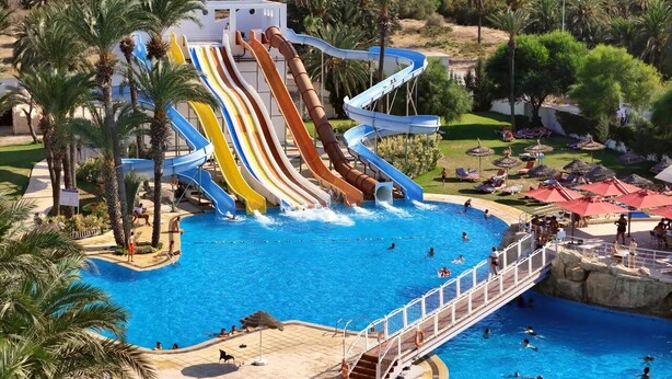 A water park with multiple slides, a swimming pool, and a bridge connecting different areas. - One Resort Jockey (Monastir)