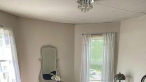 Ein Schlafzimmer mit einem großen Bett, einem Schminktisch, einem Spiegel und einem Fenster mit Vorhängen.
