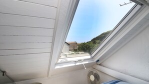 Um quarto com claraboia, janela e ventilador.