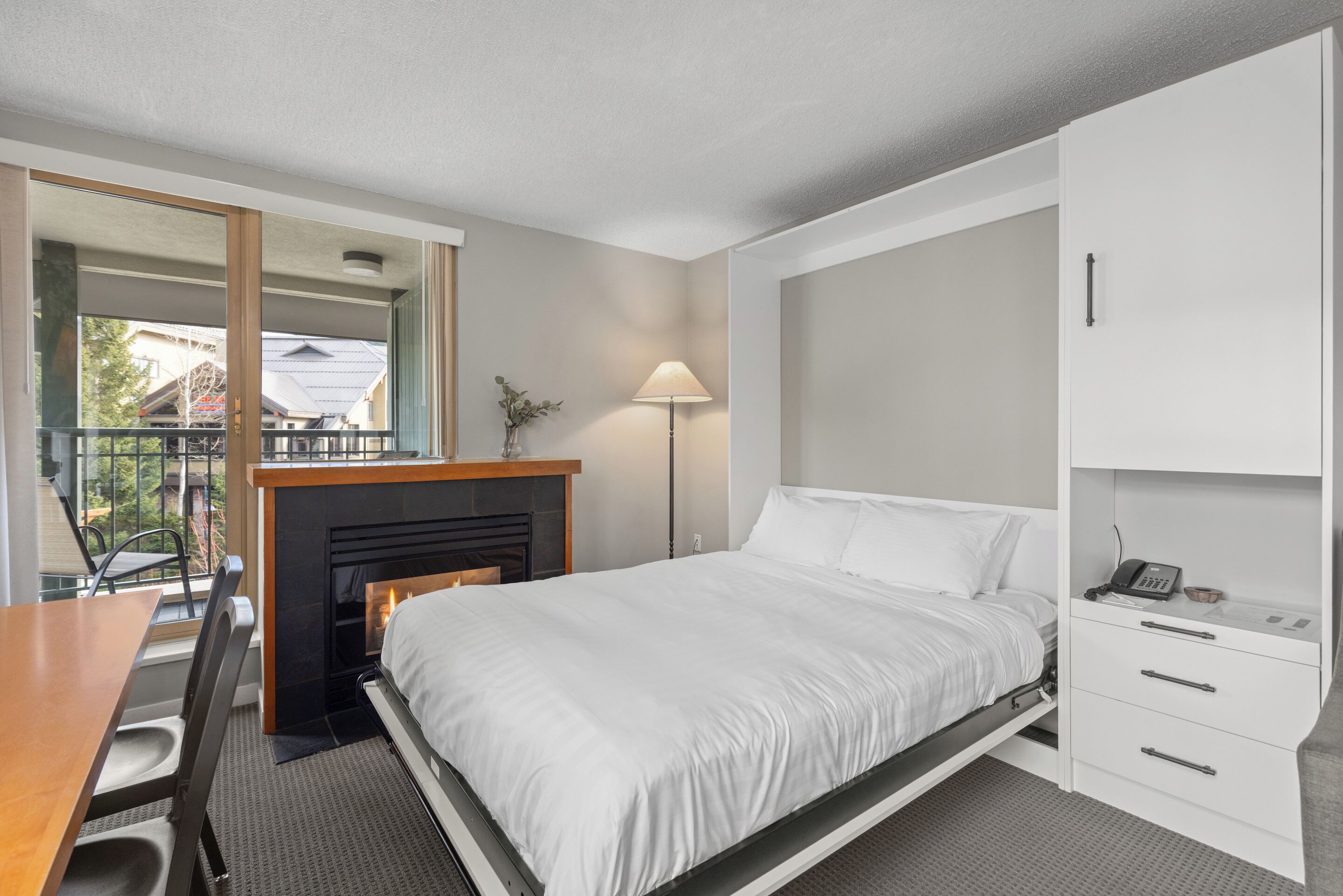 Een slaapkamer met een bed, nachtkastje, lamp en uitzicht.