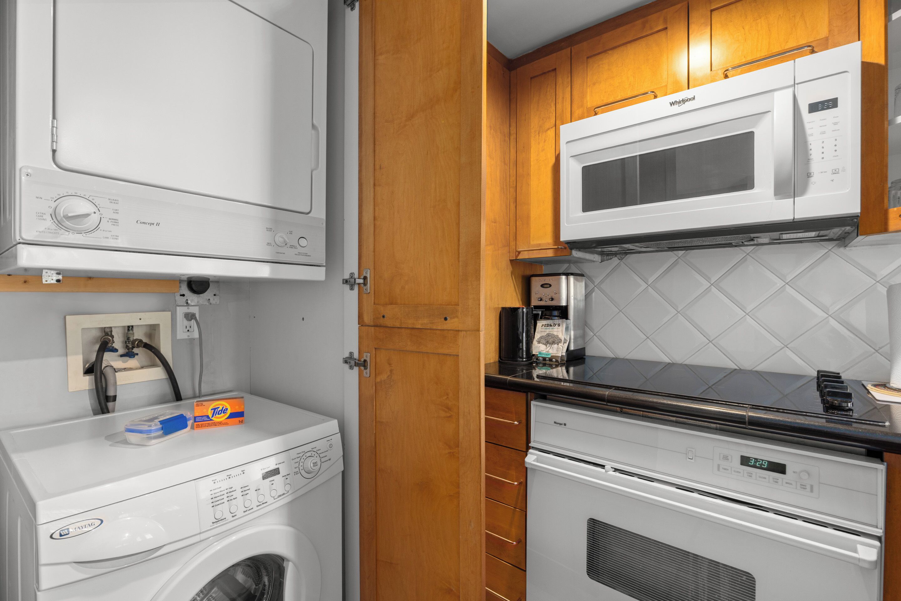 Een functionele keuken met een magnetron, koffiezetapparaat en een wasmachine.