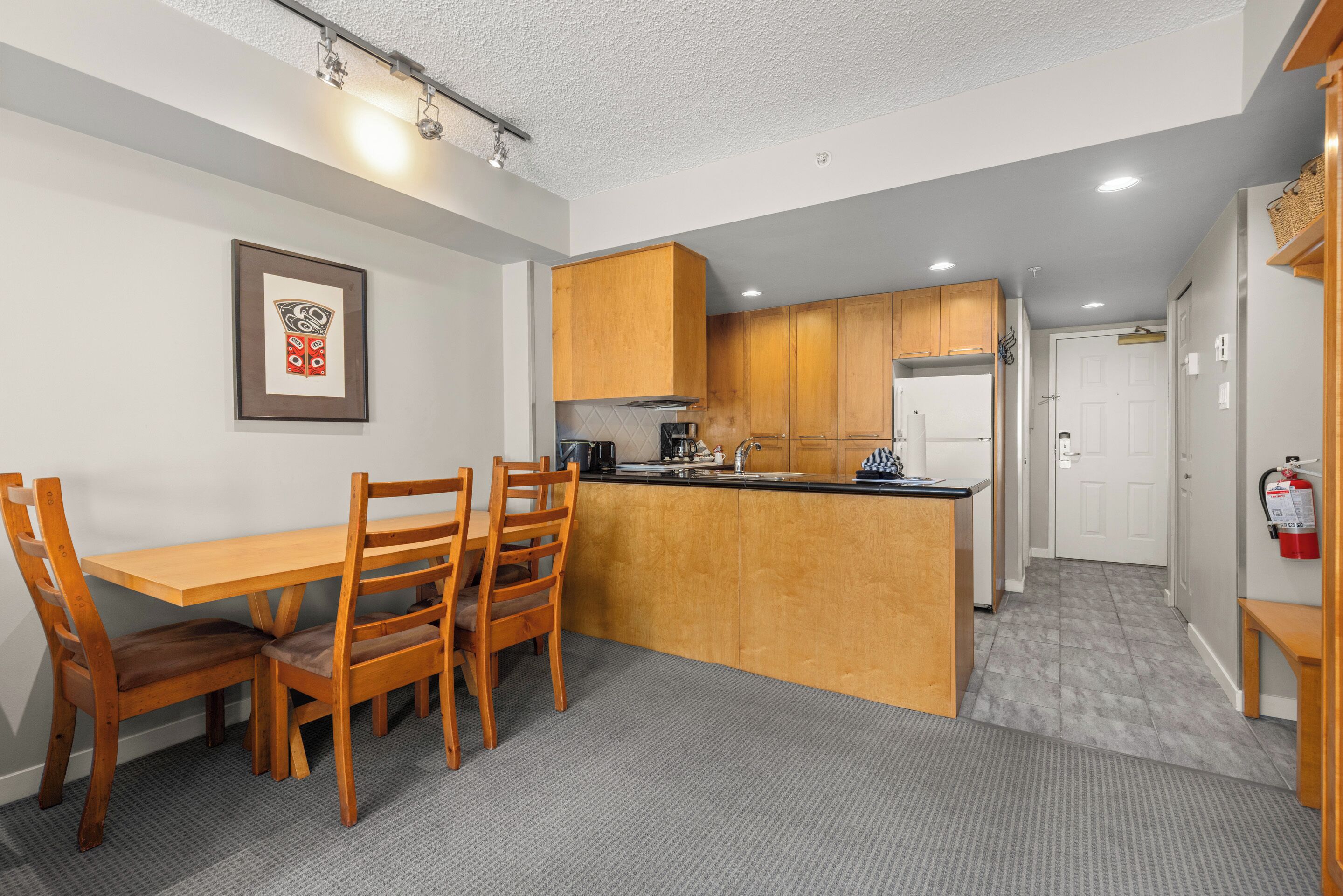 A compact kitchen with wooden cabinets, a dining table with chairs, and a small island.