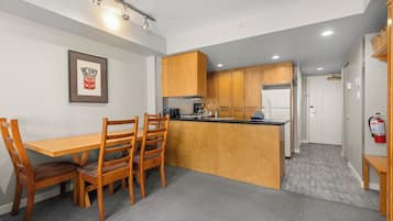 A compact kitchen with wooden cabinets, a dining table with chairs, and a small island.