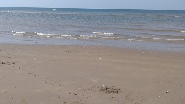 A beach with a clear sky and calm sea.