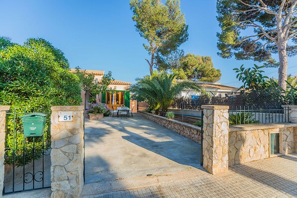 A stone gate with a mailbox, a paved pathway, and a building with a tiled roof. - house BENESTAR with pool and air conditioner (Calvià)