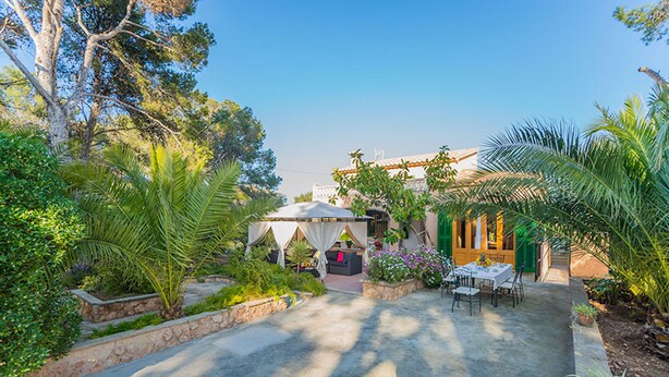 A courtyard with a dining area, a covered seating area, and lush greenery.