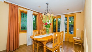 A dining room with a wooden table, chairs, a vase with flowers, and a chandelier.