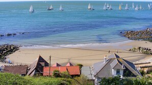 A coastal view with sailboats on the water, a sandy beach, and houses with red roofs. - Pilgrims Loft (Ventnor)