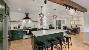 Une cuisine moderne avec des meubles de couleur verte, un grand îlot central et des tabourets de bar.