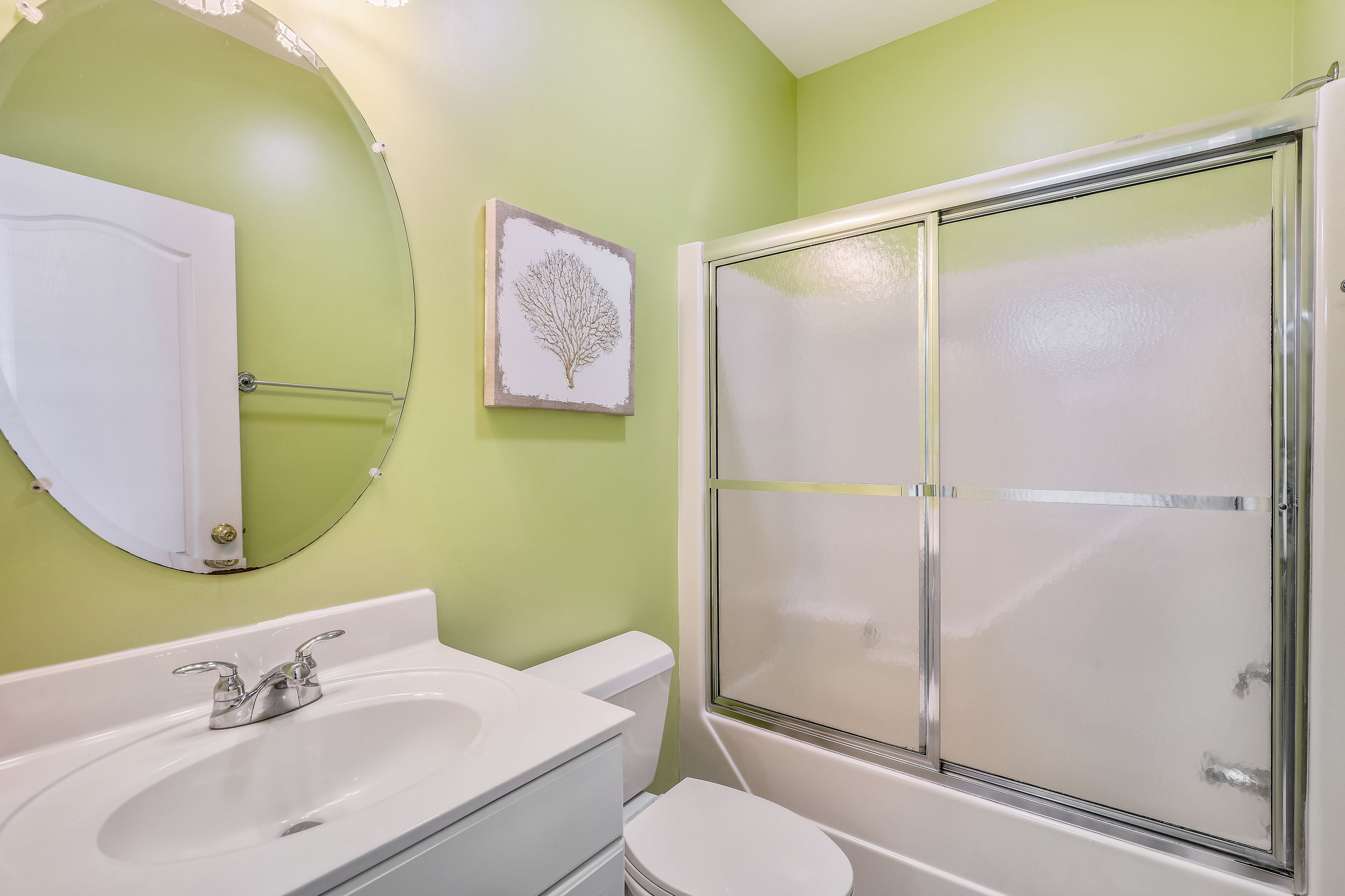 A bathroom with a white sink, toilet, and shower enclosure.