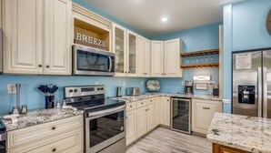 Una cocina con armarios blancos, un microondas, un horno y un refrigerador.