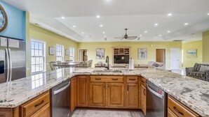 Una cocina amplia con una isla grande, armarios de madera y un refrigerador de acero inoxidable.