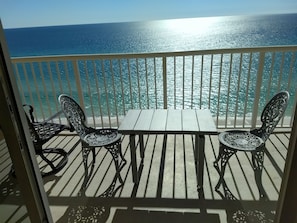 Enjoy the ocean view from this balcony with a table and two chairs.