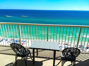Enjoy the ocean views from this balcony with a table and two chairs.