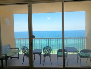 Enjoy the ocean view from this balcony with a bench, two chairs, and a table.