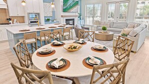 A spacious kitchen with a large island, white cabinetry, and a dining area with a round table set for six.