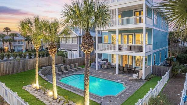 A two-story house with a swimming pool, a deck, and a fenced yard.