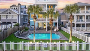 A two-story house with a backyard pool, surrounded by a white picket fence.