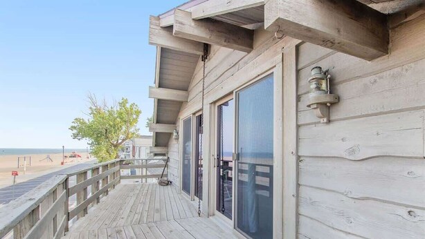 Une terrasse en bois avec une rambarde donnant sur une plage.