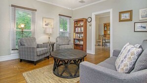 A living room with a plaid sofa, a round coffee table, a bookshelf, and a dining area with chairs and a table. - Driftwood Manor, 6BR, South Haven, Close to Beach (South Haven)