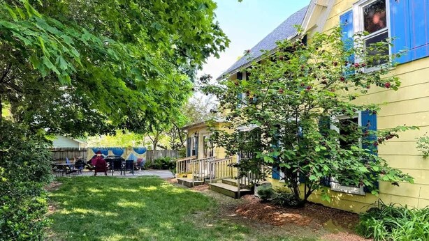 A yellow house with a porch and a small tree. - Driftwood Manor, 6BR, South Haven, Close to Beach (South Haven)