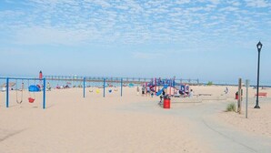 A beach with a playground, a pier in the background, and a lamp post. - Driftwood Manor, 6BR, South Haven, Close to Beach (South Haven)