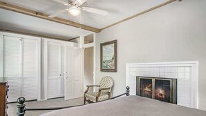 A bedroom with a bed, a fireplace, a chair, and a ceiling fan. - Driftwood Manor, 6BR, South Haven, Close to Beach (South Haven)