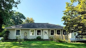 Einbungalow mit Veranda, kleinem Vorgarten und sichtbarer Garagentür.