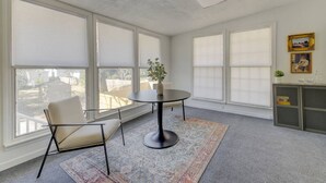 A spacious room with large windows, a round table, two chairs, a small plant, and a decorative cabinet. - Quaint 1 BR Apt | Mins from ZOO, USC & FT Jackson (Columbia)
