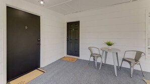 A small, enclosed room with a dark door, a white wall, a small table with two chairs, and a potted plant. - Quaint 1 BR Apt | Mins from ZOO, USC & FT Jackson (Columbia)