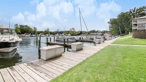 A marina with docked boats, a wooden dock, and a grassy area with a building in the background. - Mariner's Cove 8 • Riverfront • Walk To Beach (South Haven)