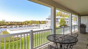A covered outdoor deck with a view of a marina and houses. - Mariner's Cove 8 • Riverfront • Walk To Beach (South Haven)