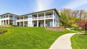 A two-story building with a covered porch and a landscaped lawn. - Mariner's Cove 8 • Riverfront • Walk To Beach (South Haven)