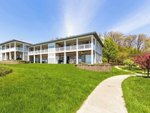 A two-story building with a covered porch and a landscaped lawn. - Mariner's Cove 8 • Riverfront • Walk To Beach (South Haven)