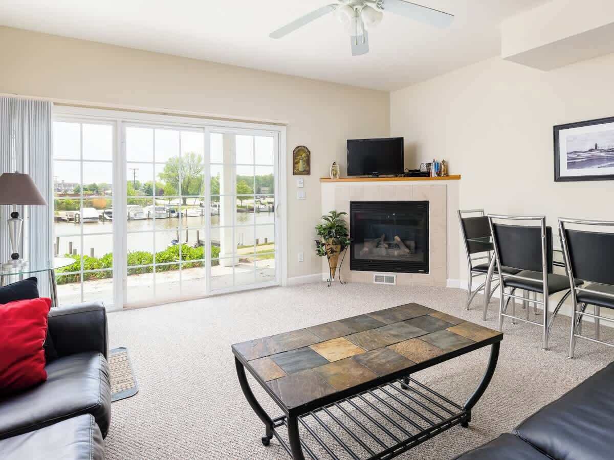 A spacious living room with a fireplace, a television, and a view through large sliding glass doors.