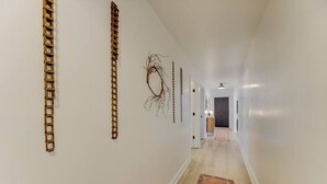 A hallway with a wooden floor, white walls, and a patterned rug. - Modern 4 BR Apt - Mins to USC, ZOO & Ft Jackson (Columbia)