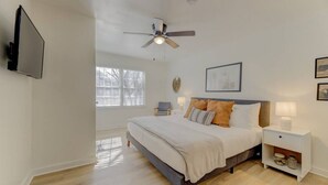 A bedroom with a bed, bedside tables, a ceiling fan, and a TV mounted on the wall. - Modern 4 BR Apt - Mins to USC, ZOO & Ft Jackson (Columbia)
