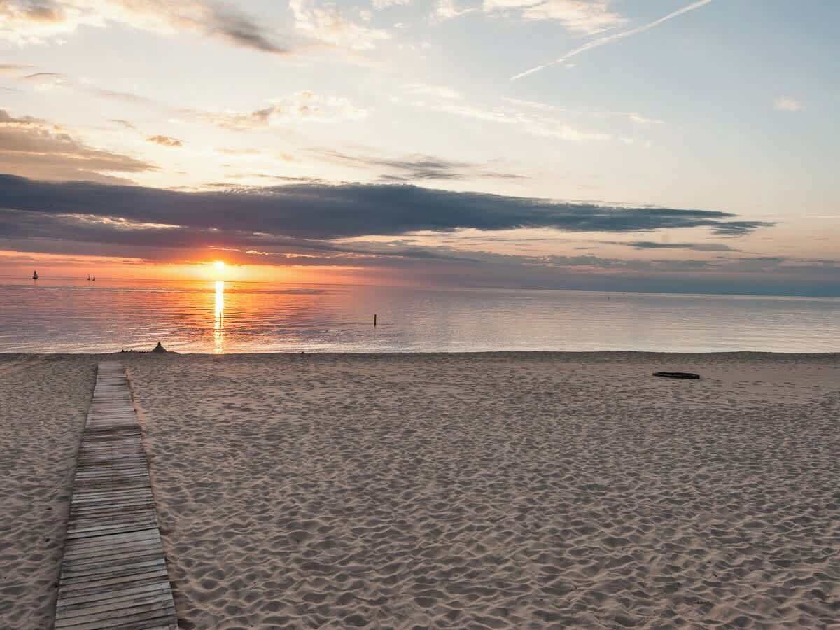 A beach with a wooden walkway leading to the water.