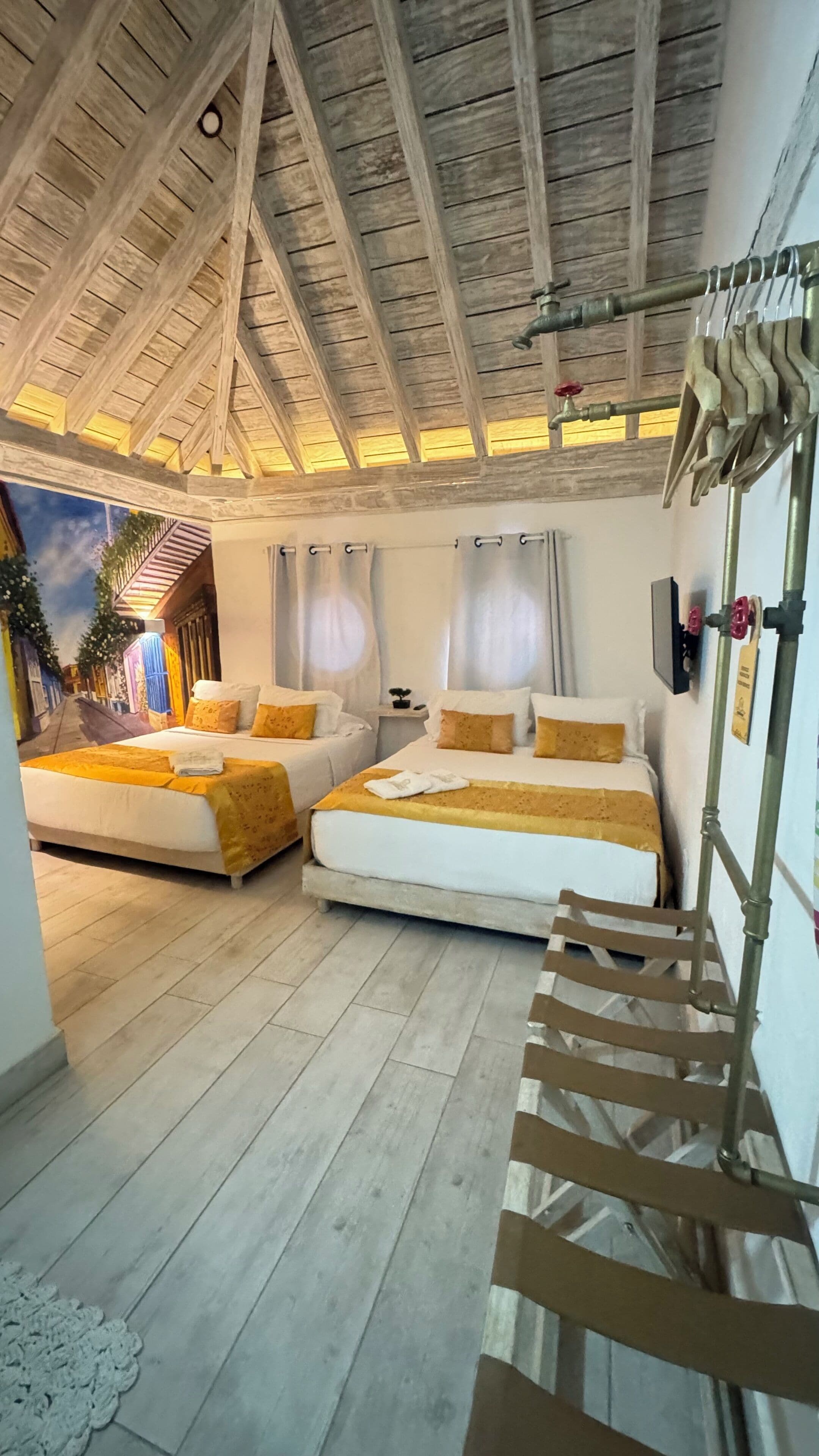 Une chambre avec deux lits, un plafond en bois et une vue sur la rue.