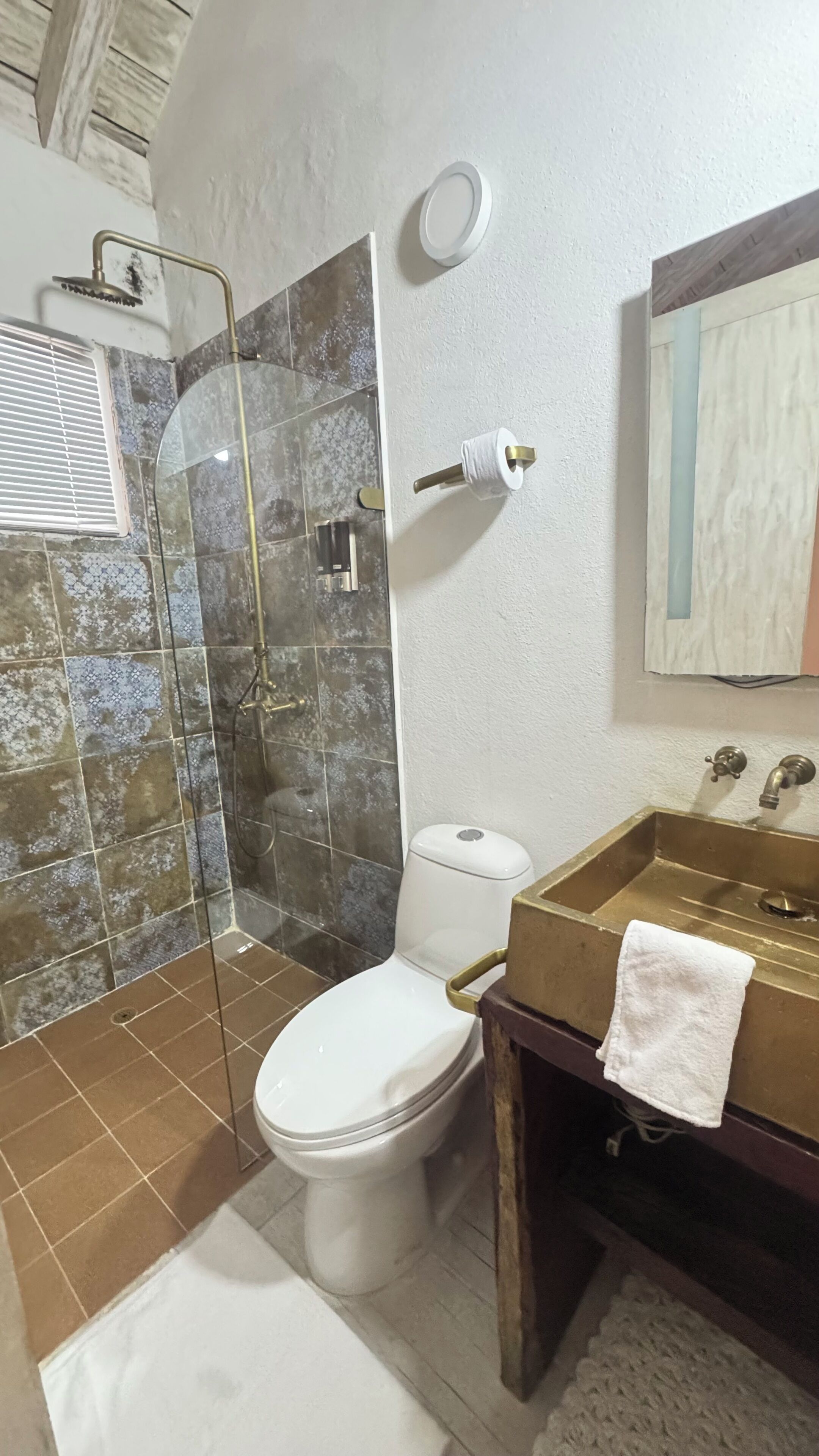 A bathroom with a glass shower enclosure, a toilet, and a sink with a towel.