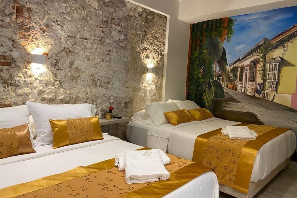 Una camera d'albergo con due letti, una parete in pietra e un murale raffigurante una scena di strada.