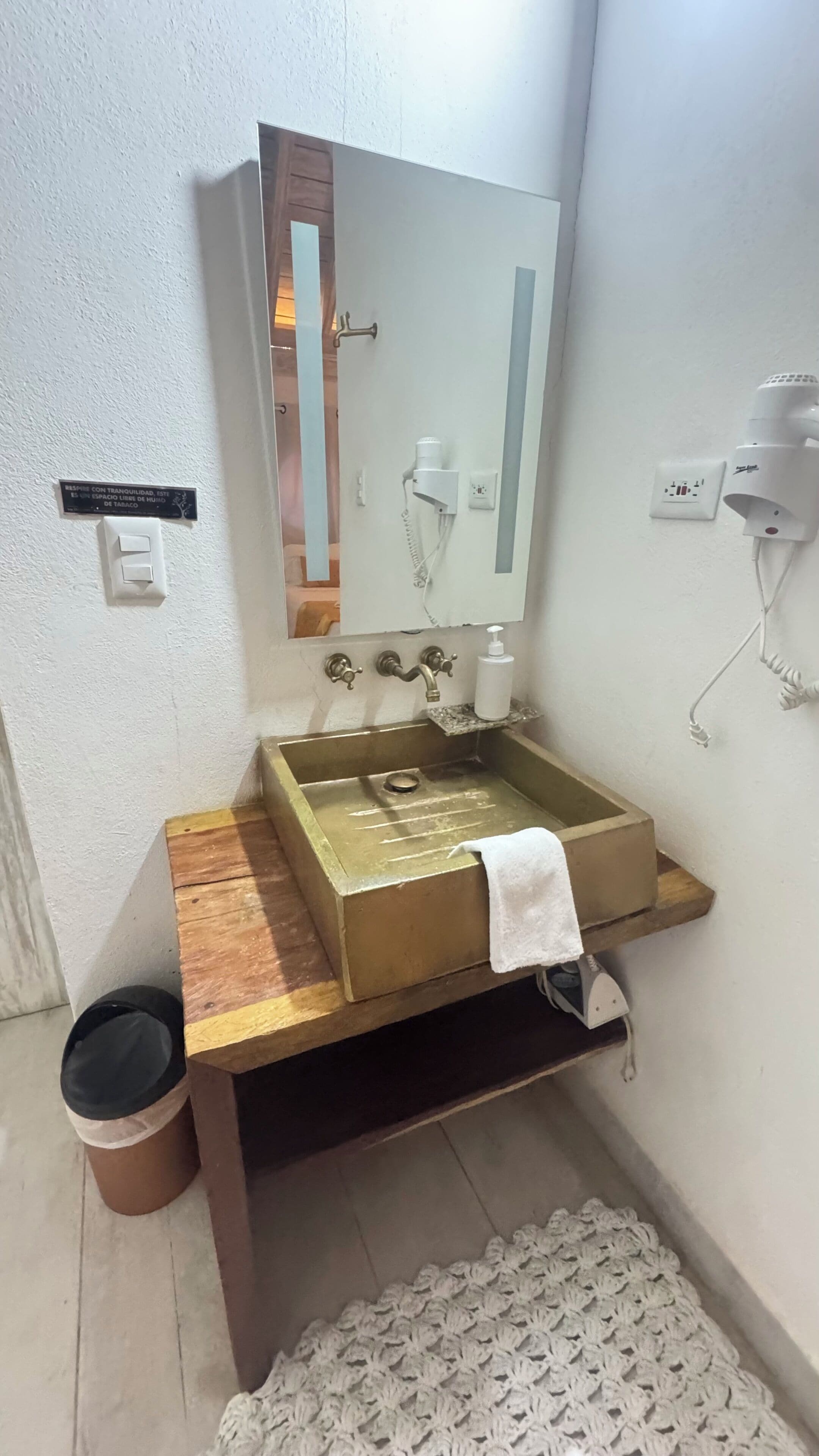 A bathroom with a wooden vanity, a sink, a towel, a mirror, and a towel rack.