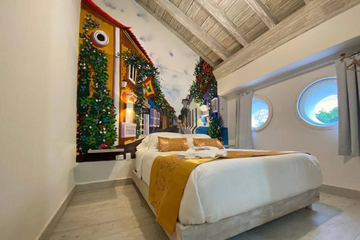 Una camera da letto con un letto grande, un murale raffigurante una scena di strada e due finestre con tende.