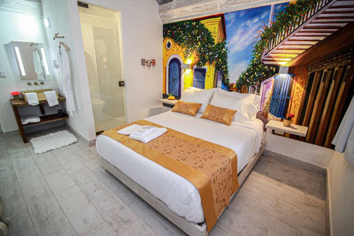 Una camera da letto con un letto grande, un bagno con lavandino e specchio, e un murale sulla parete.
