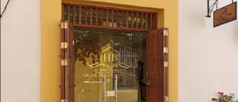 A yellow building with a large glass door and wooden shutters.